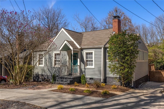 view of front of property featuring a shingled roof, fence, driveway, crawl space, and a chimney