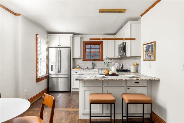 kitchen with appliances with stainless steel finishes, white cabinetry, a peninsula, and decorative backsplash