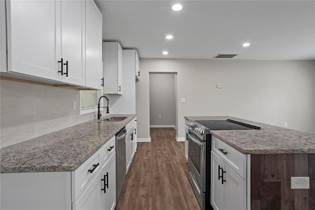 2478 Graywall St, East Point, GA 30344 - kitchen with appliances with stainless steel finishes, a sink, a center island, light stone countertops, and white cabinets