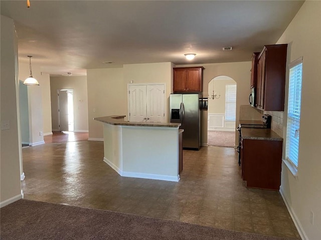 kitchen with a wealth of natural light, pendant lighting, dark tile patterned flooring, and stainless steel appliances