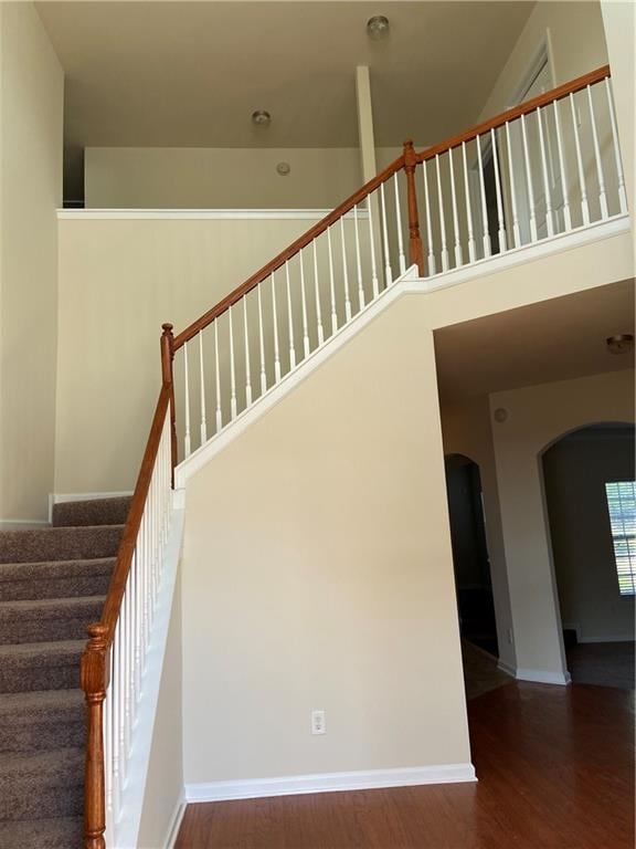 stairs featuring a high ceiling and wood-type flooring