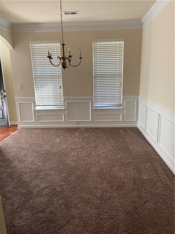 unfurnished dining area with a notable chandelier, carpet, and crown molding