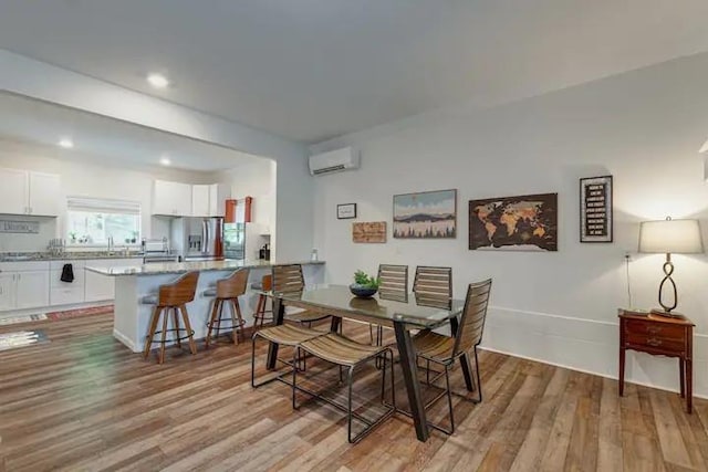 dining area with a wall mounted air conditioner and light wood-type flooring