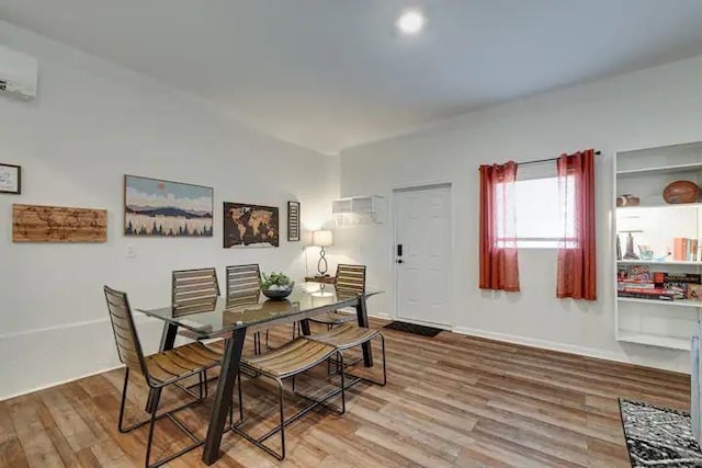 dining area with wood-type flooring and an AC wall unit