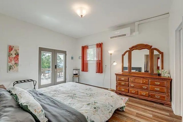 bedroom with a wall mounted air conditioner, french doors, access to outside, and light hardwood / wood-style floors