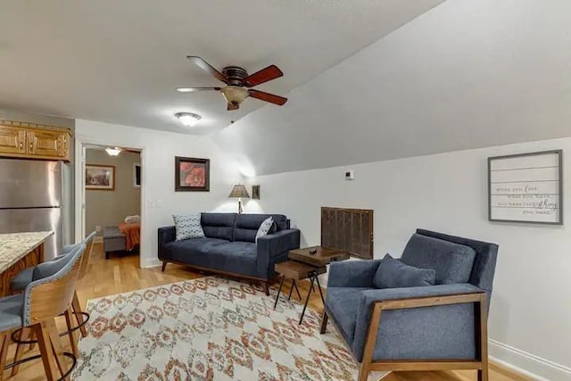 living room featuring ceiling fan, lofted ceiling, and light hardwood / wood-style flooring