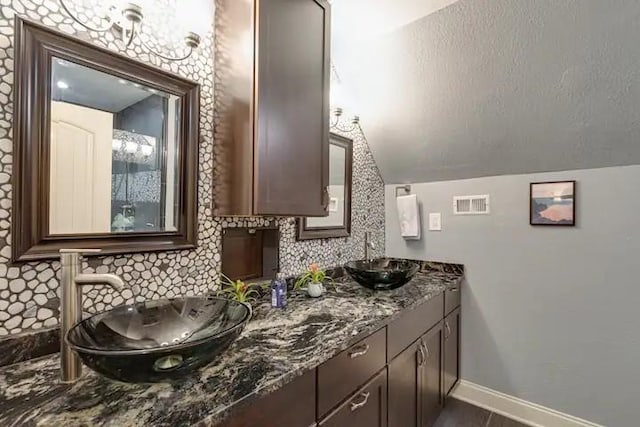 bathroom featuring decorative backsplash, vanity, and vaulted ceiling