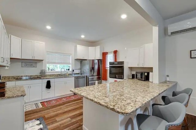 kitchen with white cabinetry, stainless steel appliances, and a wall unit AC