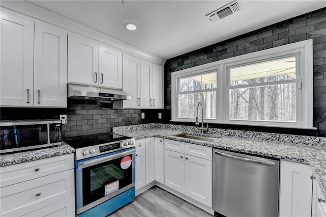 kitchen featuring visible vents, a sink, stainless steel appliances, under cabinet range hood, and white cabinetry