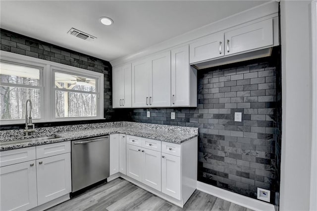 kitchen featuring visible vents, light stone countertops, light wood-style flooring, white cabinets, and stainless steel dishwasher