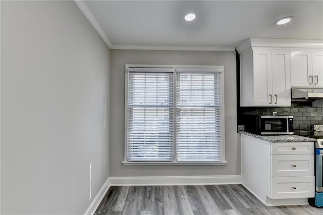 kitchen featuring backsplash, crown molding, baseboards, under cabinet range hood, and electric stove