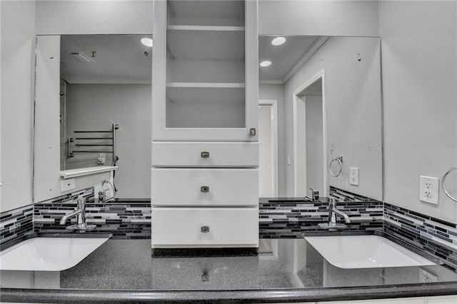 bathroom featuring a sink, decorative backsplash, and crown molding