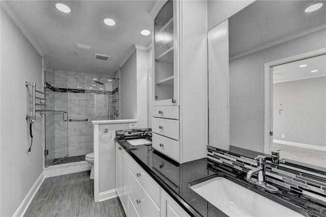 full bath with a sink, toilet, ornamental molding, and a shower stall