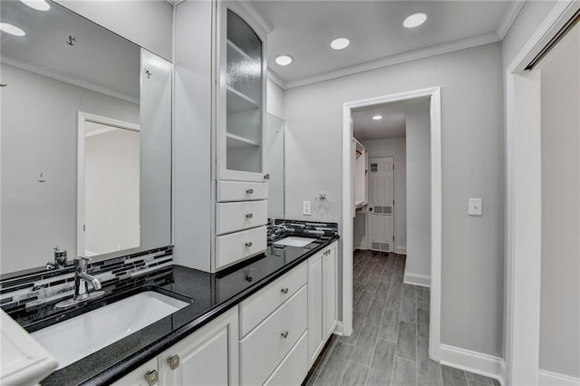 full bathroom featuring wood tiled floor, ornamental molding, baseboards, and a sink