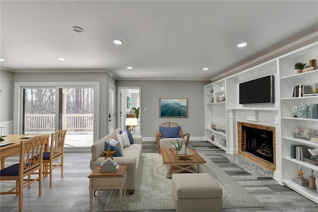 living area with built in shelves, wood finished floors, a fireplace, recessed lighting, and crown molding