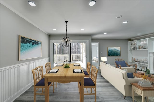 dining room featuring wood finished floors, a wainscoted wall, recessed lighting, crown molding, and a notable chandelier