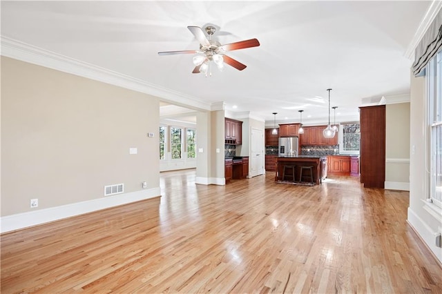 unfurnished living room featuring crown molding, visible vents, light wood-style flooring, ceiling fan, and baseboards