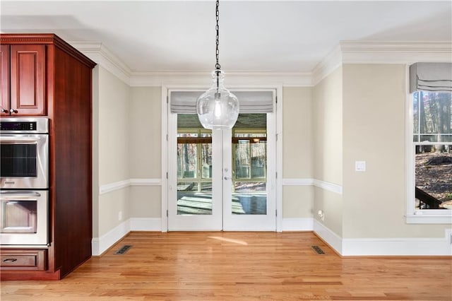 unfurnished dining area featuring ornamental molding, light wood-type flooring, visible vents, and baseboards