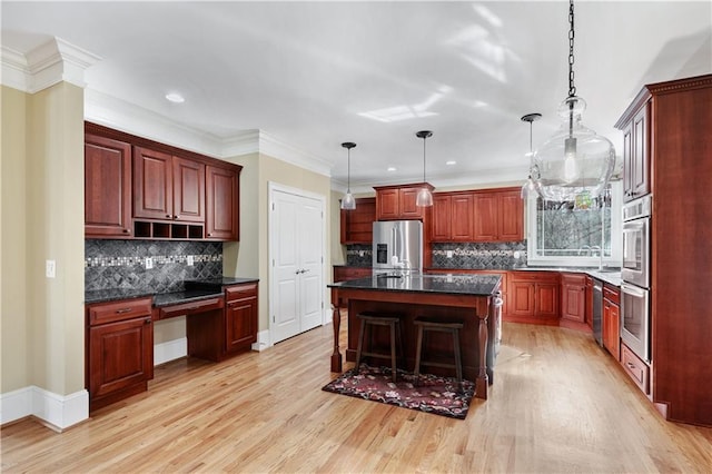 kitchen featuring reddish brown cabinets, a kitchen island, stainless steel appliances, pendant lighting, and built in desk