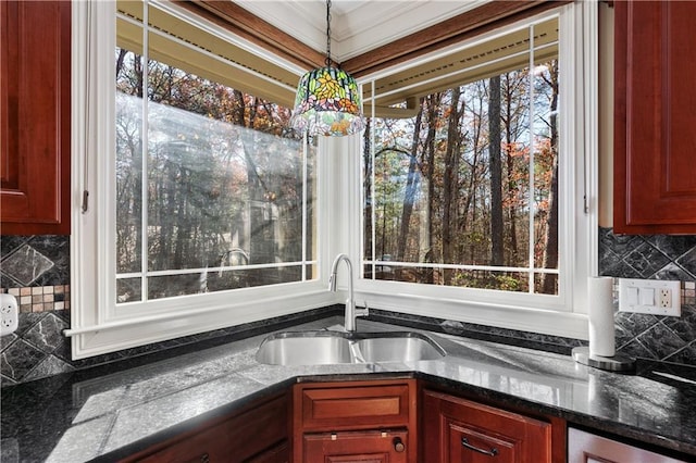 kitchen featuring hanging light fixtures, dark brown cabinets, dark countertops, and a sink