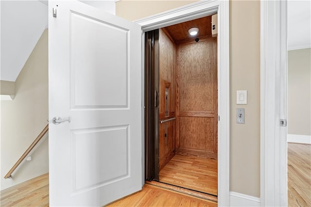 hallway featuring elevator and light wood finished floors