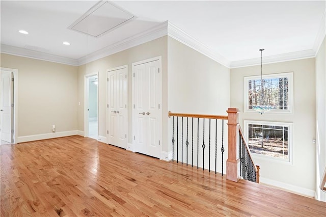 interior space with attic access, baseboards, light wood-style flooring, and crown molding