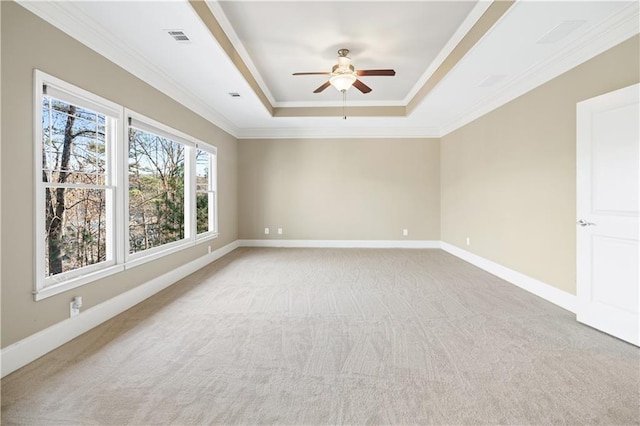 spare room featuring a tray ceiling, visible vents, ornamental molding, light carpet, and baseboards