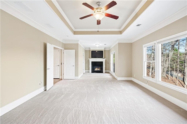 unfurnished living room with a tray ceiling, a warm lit fireplace, light carpet, and baseboards