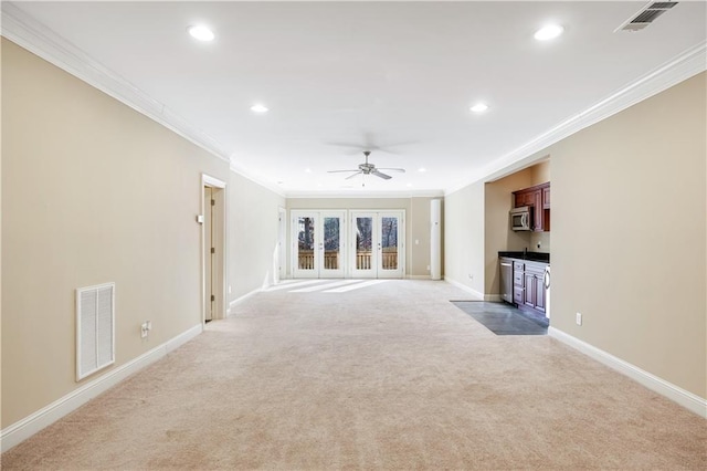 unfurnished living room featuring light colored carpet, visible vents, ceiling fan, and baseboards