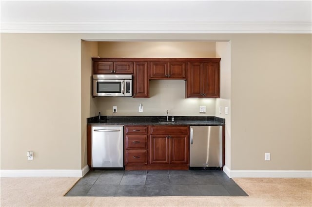 kitchen with stainless steel appliances, dark stone counters, a sink, and dark colored carpet