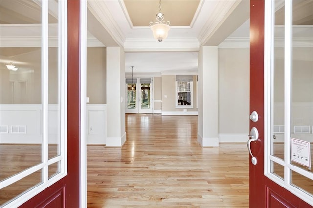 foyer entrance with visible vents, crown molding, and light wood finished floors