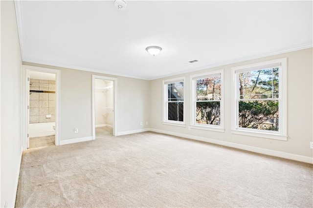 unfurnished bedroom featuring visible vents, baseboards, light colored carpet, ornamental molding, and a spacious closet