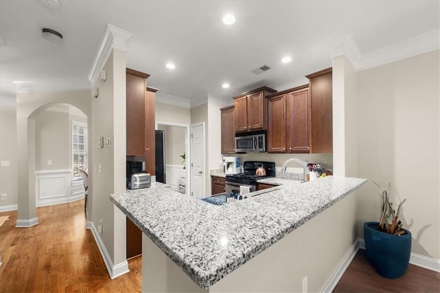 3937 Covey Flush Ct SW Unit 25, Smyrna, GA 30082 - kitchen with stainless steel appliances, arched walkways, light wood-type flooring, light stone countertops, and ornamental molding
