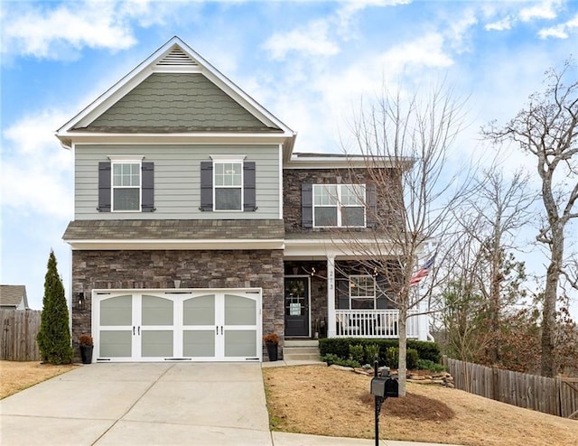 craftsman inspired home with covered porch, fence, a garage, stone siding, and driveway