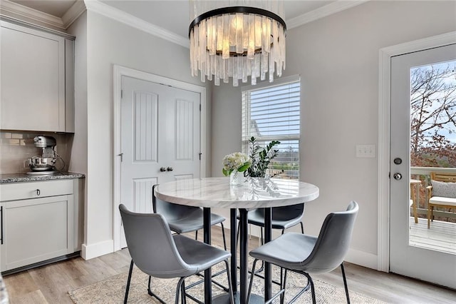 dining room with baseboards, ornamental molding, light wood-type flooring, and a healthy amount of sunlight