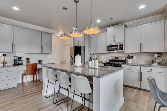 kitchen with stainless steel appliances, light stone counters, light wood-type flooring, and gray cabinetry