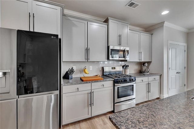 kitchen with visible vents, decorative backsplash, ornamental molding, stainless steel appliances, and light wood-type flooring