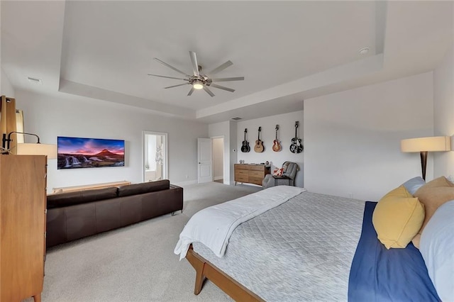 carpeted bedroom with a raised ceiling and a ceiling fan