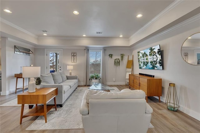 living room with light wood finished floors, baseboards, visible vents, and ornamental molding