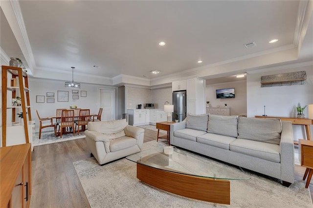 living area featuring recessed lighting, visible vents, crown molding, and light wood-style flooring