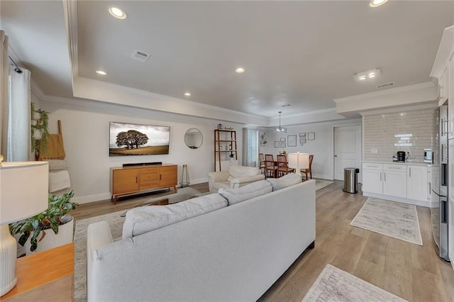 living room with recessed lighting, visible vents, crown molding, and light wood finished floors