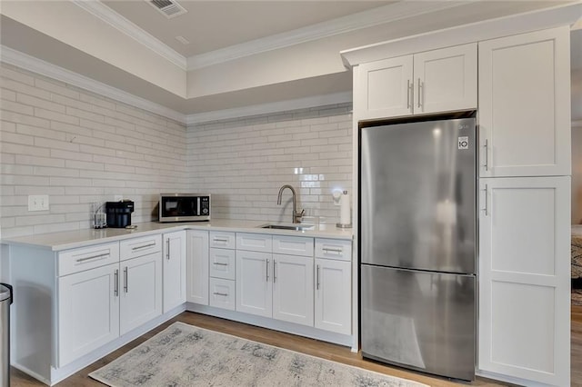 kitchen featuring a sink, visible vents, light countertops, appliances with stainless steel finishes, and crown molding