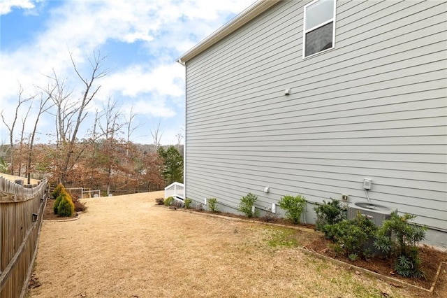 view of side of home featuring central air condition unit, fence, and a lawn