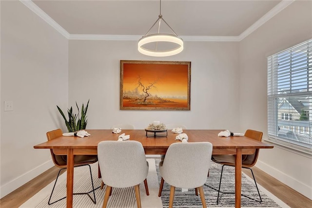 dining area featuring light wood finished floors, baseboards, and crown molding