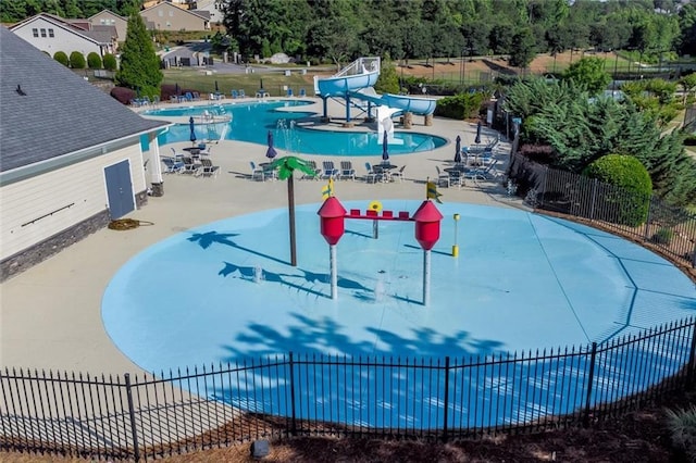 pool featuring a water slide, fence, and a patio