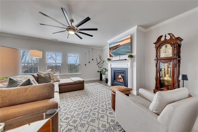 living area with visible vents, baseboards, light wood finished floors, a glass covered fireplace, and crown molding