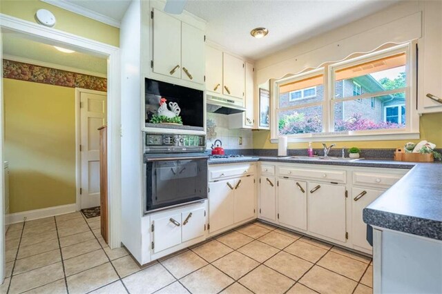 268 Tuck St, Cedartown, GA 30125 - kitchen with black oven, a sink, dark countertops, light tile patterned floors, and crown molding