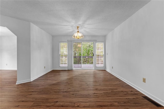 unfurnished room with a notable chandelier, dark wood-type flooring, and a textured ceiling