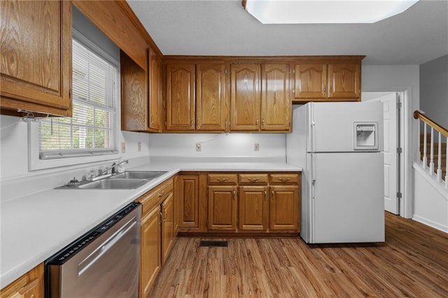 kitchen featuring stainless steel dishwasher, sink, white refrigerator with ice dispenser, and light hardwood / wood-style flooring