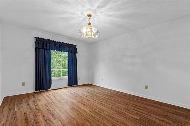 empty room with an inviting chandelier and wood-type flooring